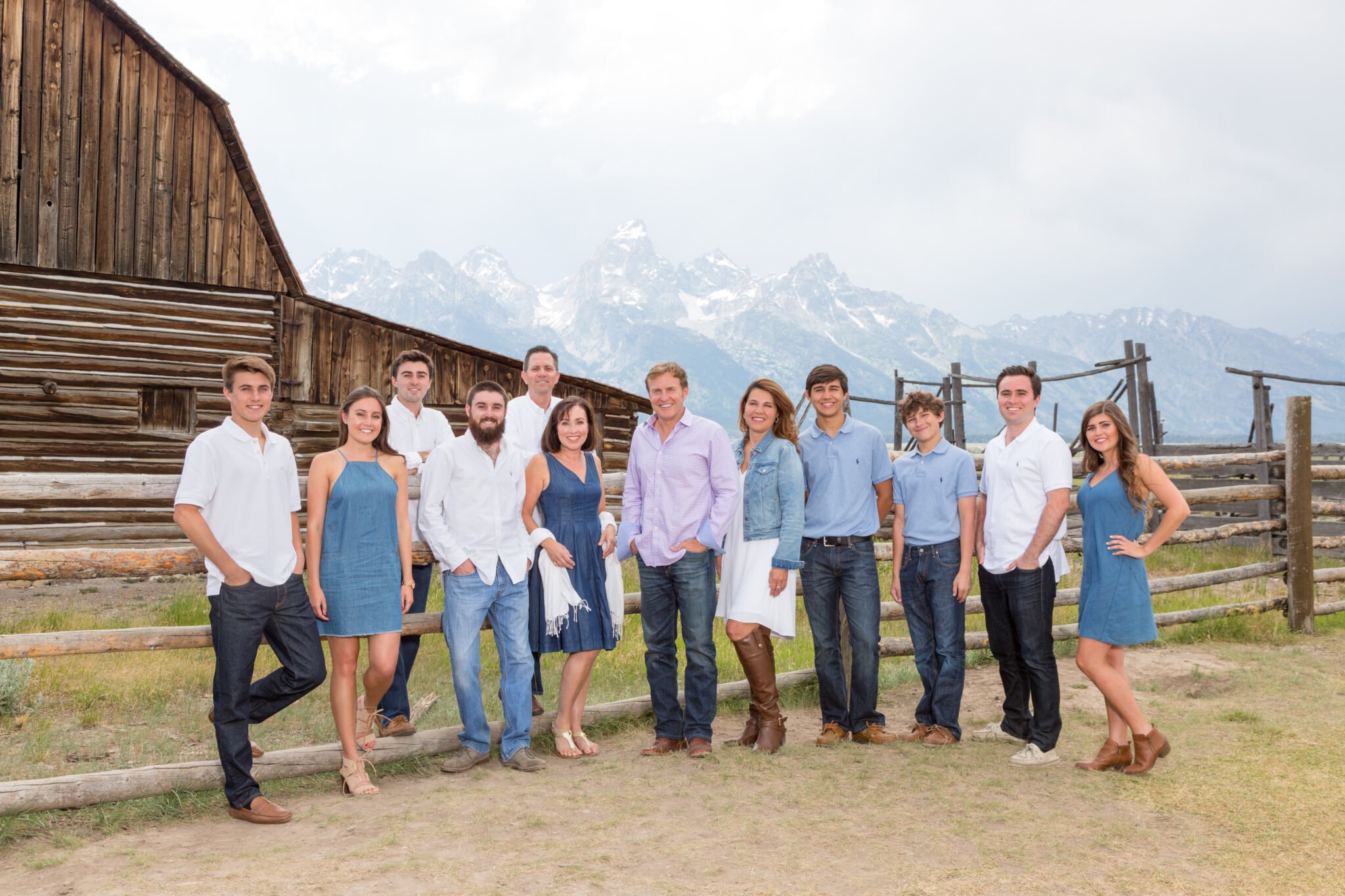 A family portrait of 12 in Grand Teton National Park in front of Moulton Barn