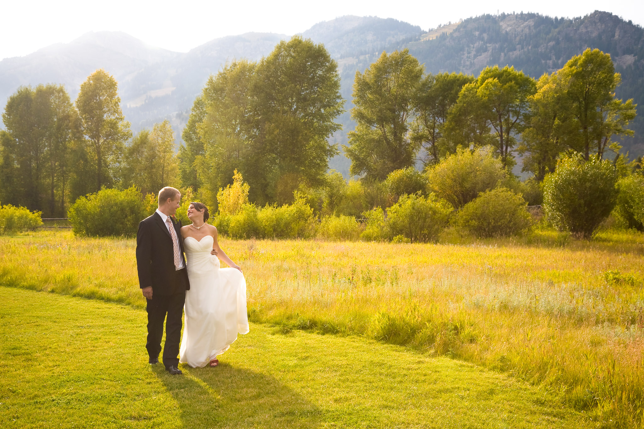 A bride and groom walk among the golden fall colors in Jackson Hole Wyoming
